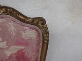 a pink and gold chair against a white wall