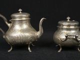 pair of antique silver teapots on black background with black background