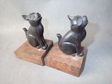 two statues of cats sitting on a wooden block