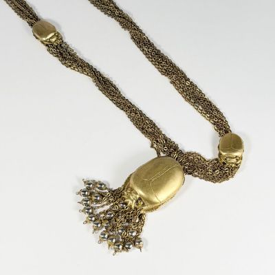 un gros plan d'un collier en or orné d'un pompon, posé sur une surface blanche