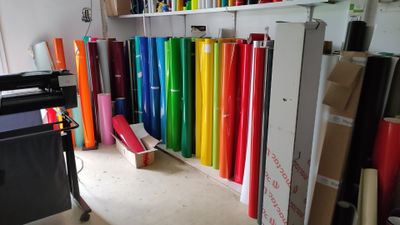 many rolls of colored paper on a shelf in a room