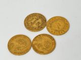 quatre pièces d'or sont représentées sur une surface blanche