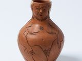 un petit vase marron sur lequel est représentée une femme
