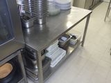 une cuisine avec une table en inox sur laquelle sont posées des assiettes et des casseroles