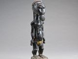 Une statue représentant une femme coiffée d'une coiffe se dresse sur un socle