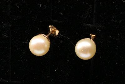 a pair of pearl earrings on a black velvet surface