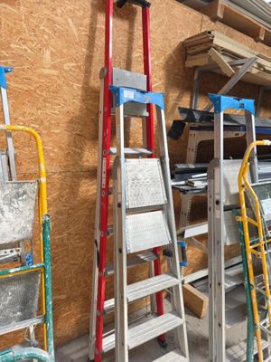 Plusieurs échelles sont alignées contre le mur d'un immeuble