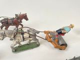 three figurines of horses pulling a man on a sleigh