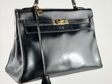 a black leather handbag with gold hardware on the handle
