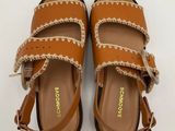 a pair of brown sandals on a white surface