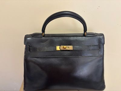 a black leather handbag sitting on top of a wooden table
