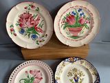 trois assiettes ornées de motifs floraux, posées sur un support en bois