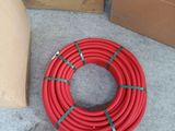a red hose sitting on the ground next to a cardboard box