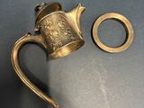 a brass teapot and a brass ring on a table