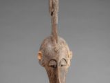 a wooden mask with a bird ' s head on a stand