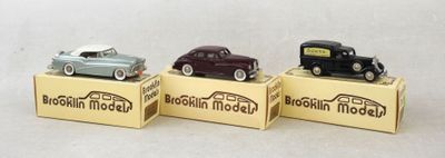 trois petites voitures miniatures sont posées sur des boîtes, sur une surface blanche