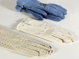 three pairs of white gloves and a pair of blue gloves on a white surface