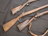 three old guns are laying on a black cloth with a leather strap