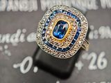 un gros plan d'une bague sertie d'un diamant et d'un saphir posée sur une feuille de papier