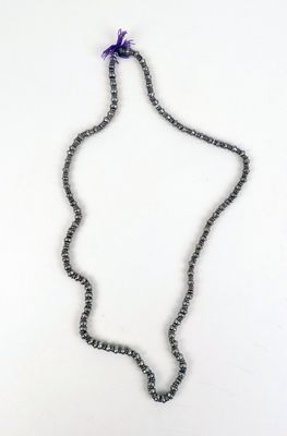 un gros plan d'un collier posé sur une surface blanche, avec une fleur violette