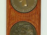 wooden plaque with two medallions of a woman and a man on it