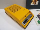 a yellow radio sitting next to a book on a table