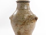 a brown vase with a lid sitting on a white surface