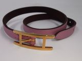 ceinture en cuir rose et noir avec une boucle dorée sur un fond blanc