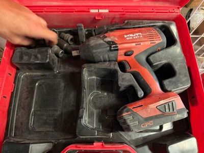 quelqu'un tient une perceuse sans fil dans une boîte à outils rouge