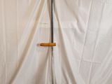 a metal pole with a wooden handle on a white sheet