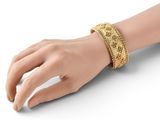 the woman is wearing a gold bracelet with a snake skin pattern
