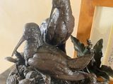 une statue représentant un oiseau posé sur une table, à côté d'un cadre photo