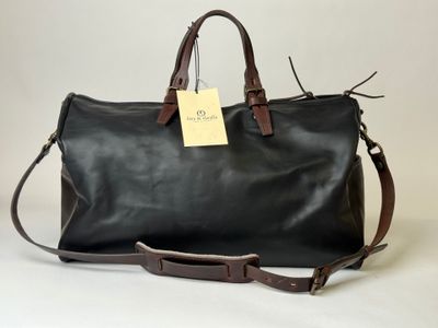 a black leather duffel bag with a tag attached to it
