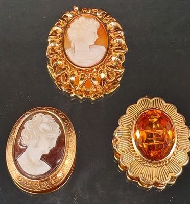 trois broches de couleur or ornées de camées représentant une femme et un homme