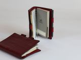 un portefeuille posé sur une surface blanche, à côté d'un livre ouvert, sur fond blanc