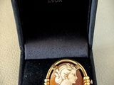 une image représentant une broche plaquée or sur laquelle figure le visage d'une femme