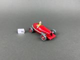 a red toy car with a man in the driver ' s seat next to a white tag