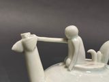 a white teapot with a man and a dog on it
