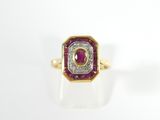 a close up of a gold ring with a ruby and diamond center