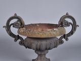 a small metal bowl with a handle on a pedestal