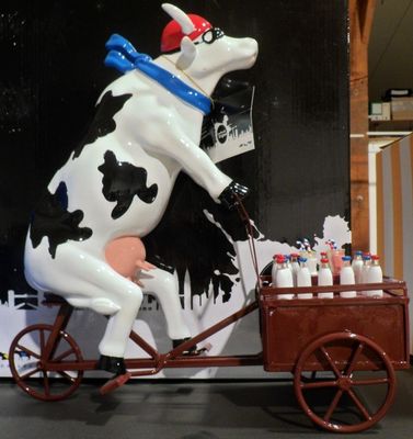 une statue représentant une vache à vélo tirant une charrette remplie de peinture