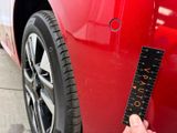 a hand holding a ruler that is on the side of a red car