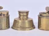 three antique brass containers with lids on a white surface