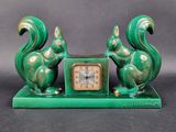 une horloge verte sur laquelle sont assis deux écureuils