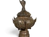 an image of a bronze vase with a bird on top of it