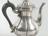 an antique silver teapot with a black handle on a white background