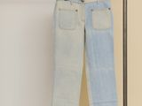 two pairs of jeans hanging on a clothes rack in a room