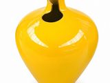 a yellow vase with a hole in it on a white surface