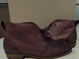 des bottes en cuir bordeaux avec des lacets, posées sur une table