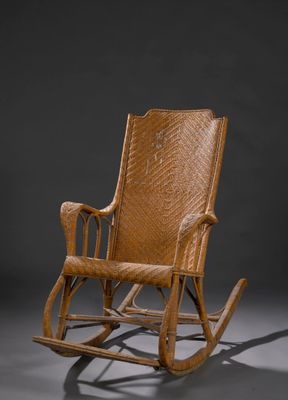un fauteuil à bascule en bois avec une assise en osier, sur fond gris